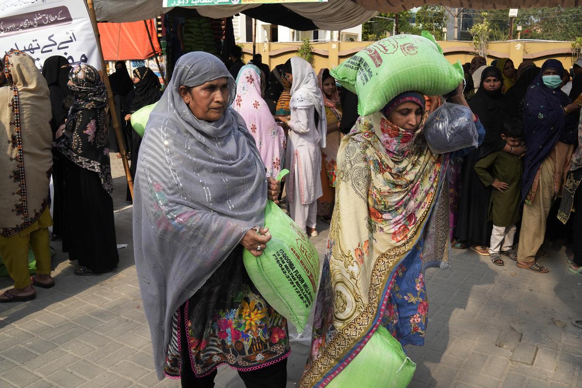 Women leave while others wait their turn to get a free sack of wheat flour at a distribution point, in Lahore, Pakistan on Thursday, March 30. 