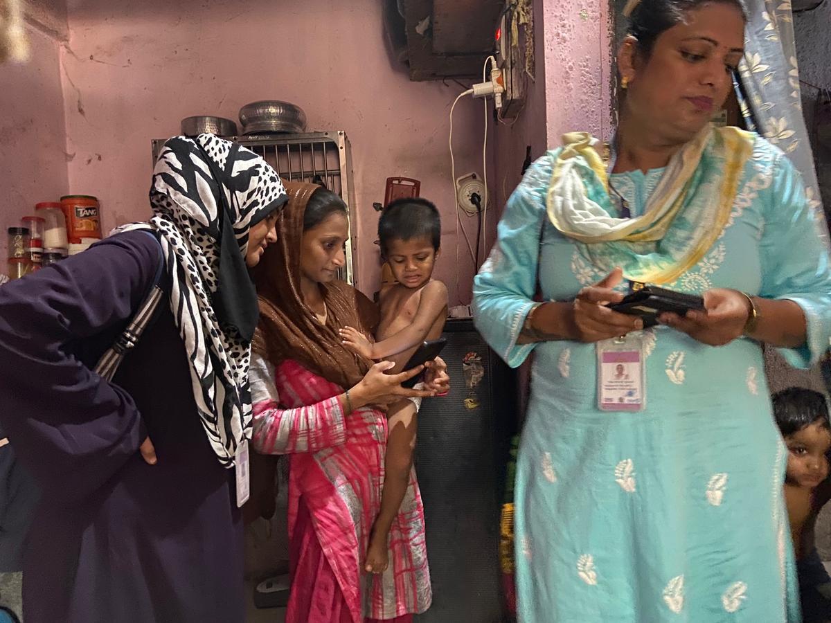 Transgender field coordinator Tulsi (right) and team member Sana (far left) with a family in Mumbra-Kausa.