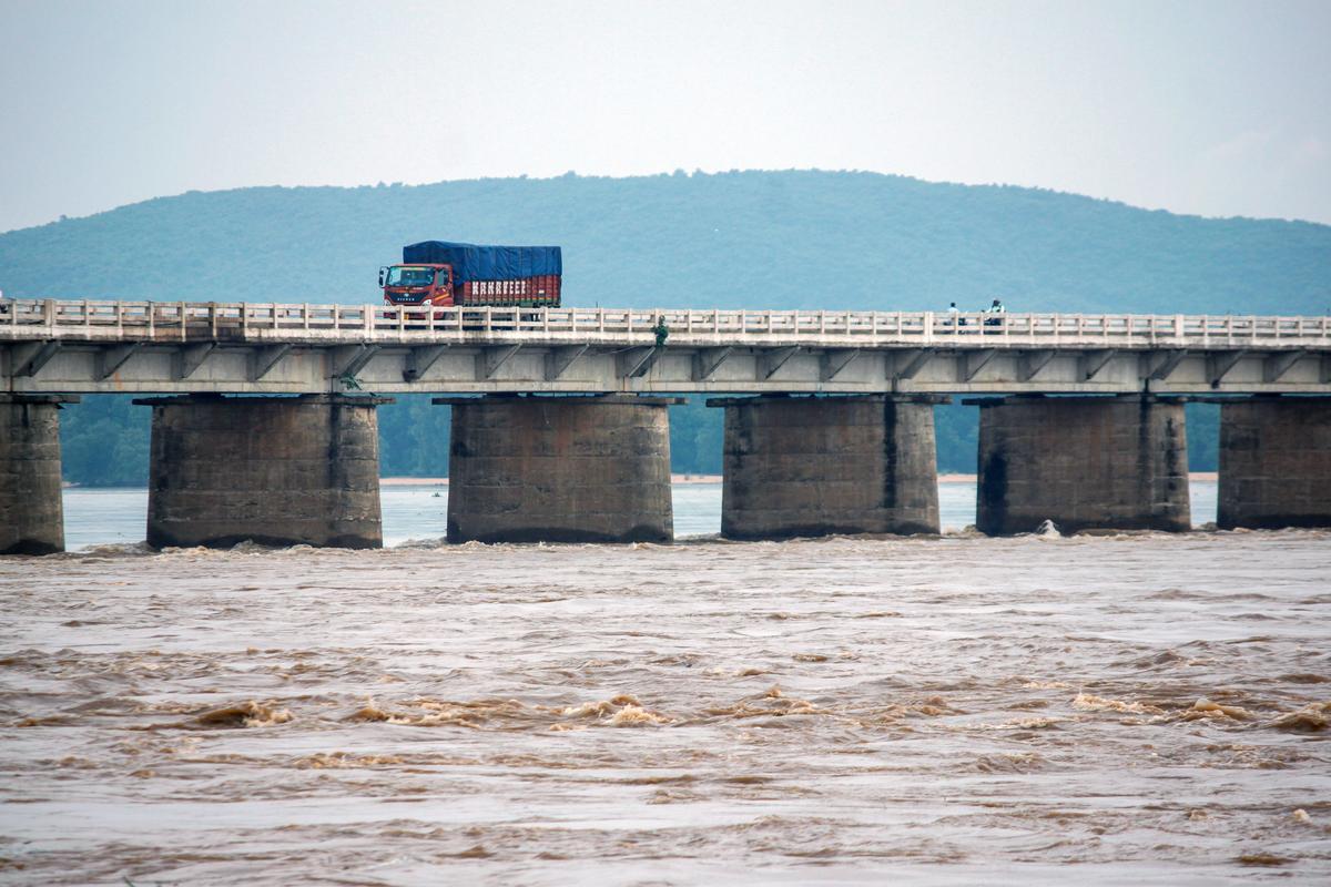 A truck passes over a bridge while floodwater of the Mahanadi river is released from the Hirakud Dam.