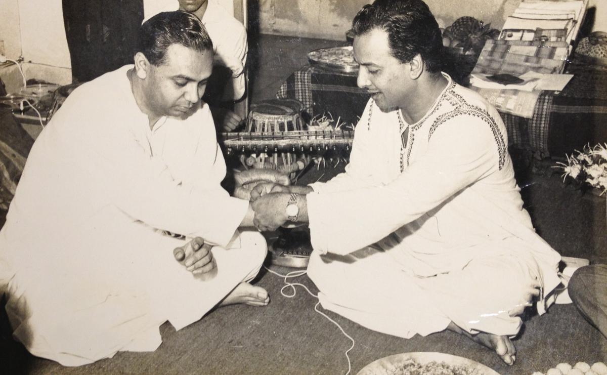 Ustad Vilayat Khan tying the ganda (thread) on shagird (student) Arvind Parikh. The thread signifies the guru-sishya parampara