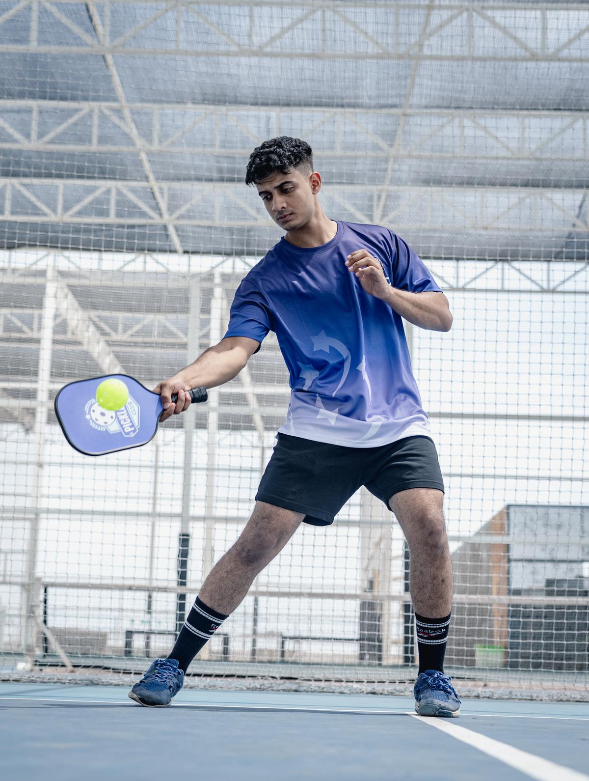 A person actively playing pickleball on a court with a paddle and ball.