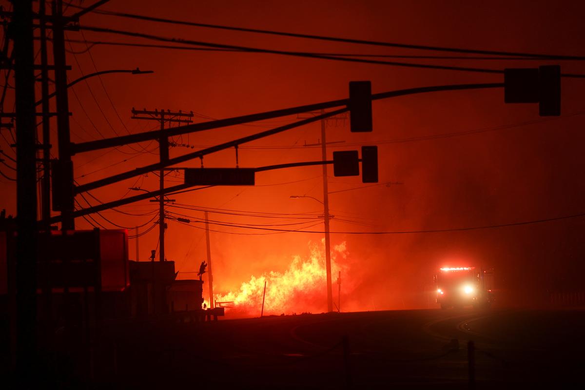 A firetruck drives past flames along the Pacific Coast Highway, as a wildfire burns in the Pacific Palisades neighborhood of west Los Angeles, California, U.S. on January 7, 2025. 