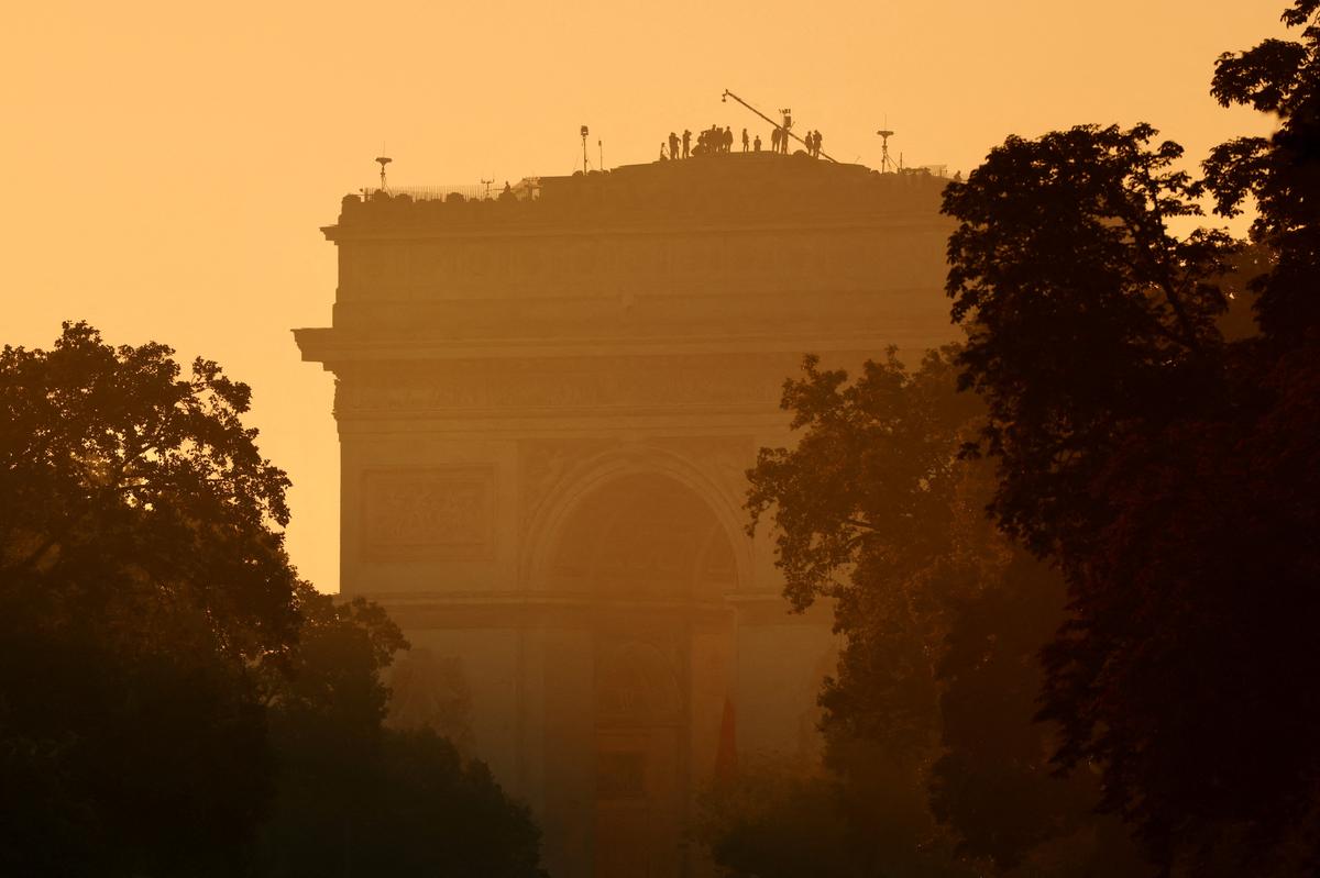 Military technicians and members of the media stand on the roof of the Arc de Triomphe at sunrise, ahead of the Bastille Day parade in Paris, on July 14, 2024