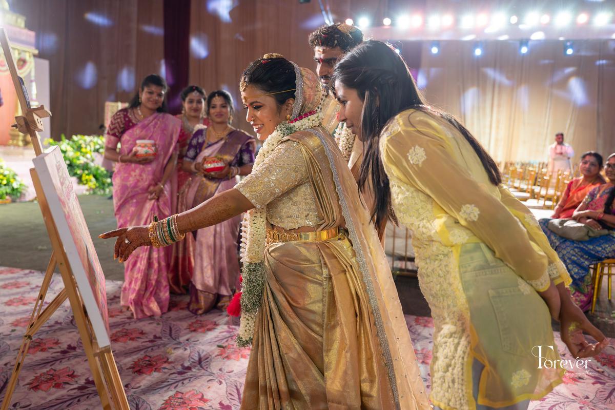 Keerthana Adepu (right) looks at her art with the bride and the groom