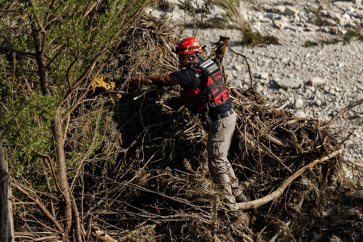 A member of a search and rescue team checks debris for any survivors or remains of the deceased on the bank of the Guadalupe River A member of a search and rescue team checks debris for any survivors or remains of the deceased on the bank of the Guadalupe River