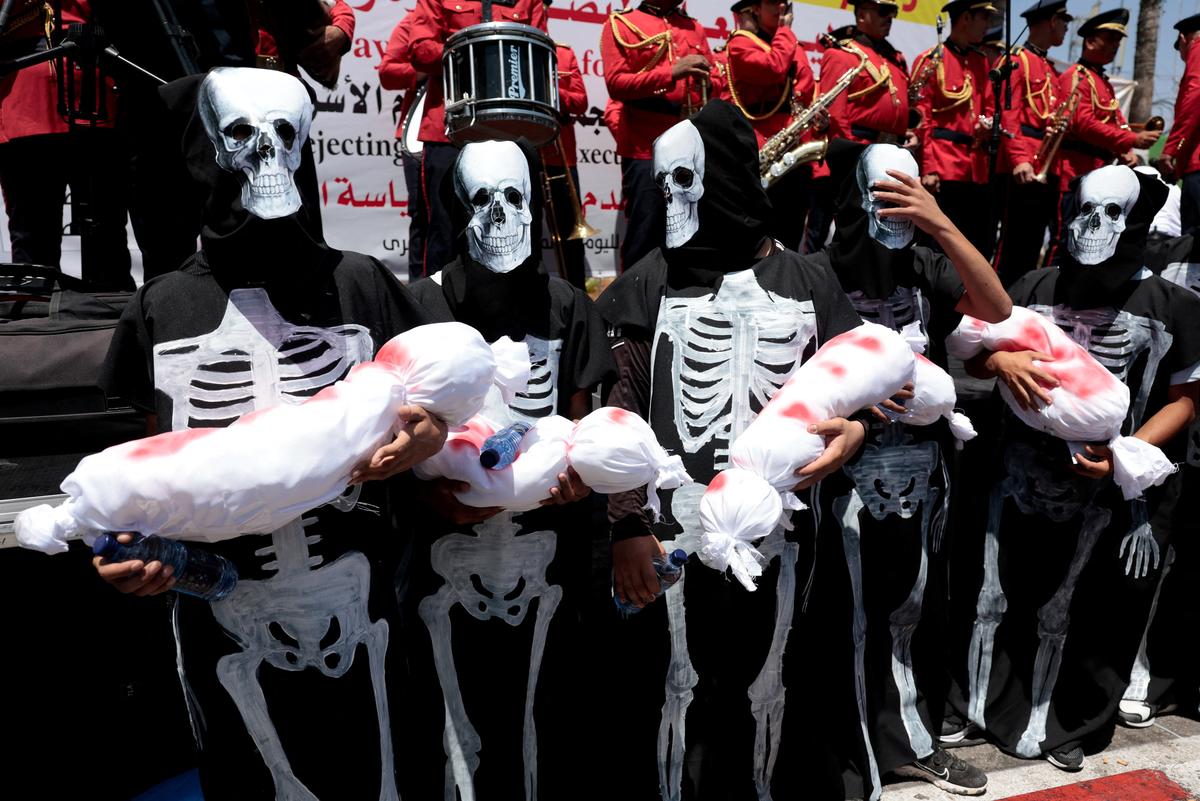 Demonstrators, dressed in costumes depicting skeletons, hold props representing dead babies, during a protest in solidarity with Gaza and Palestinian prisoners in Israeli jails, in Ramallah in the Israeli-occupied West Bank, August 3, 2025. 