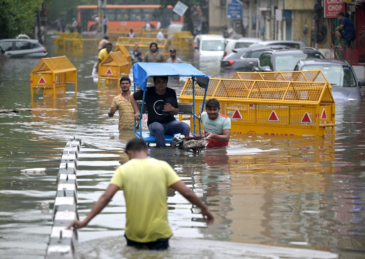 Seorang penarik becak keluar melalui jalan yang tergenang air di New Delhi pada 28 Juni 2024.
