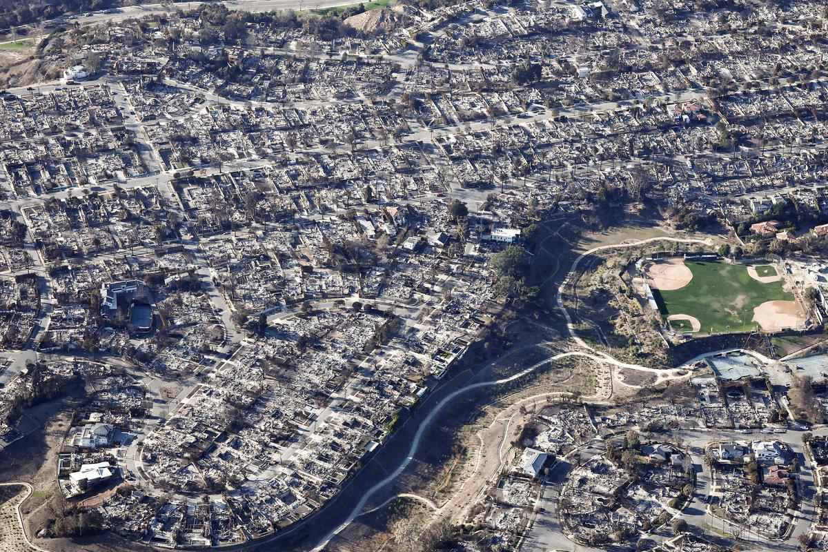 An aerial view shows homes destroyed in the Palisades Fire near a baseball and softball field as wildfires cause damage and loss through the LA region on January 13, 2025 in Pacific Palisades, California.