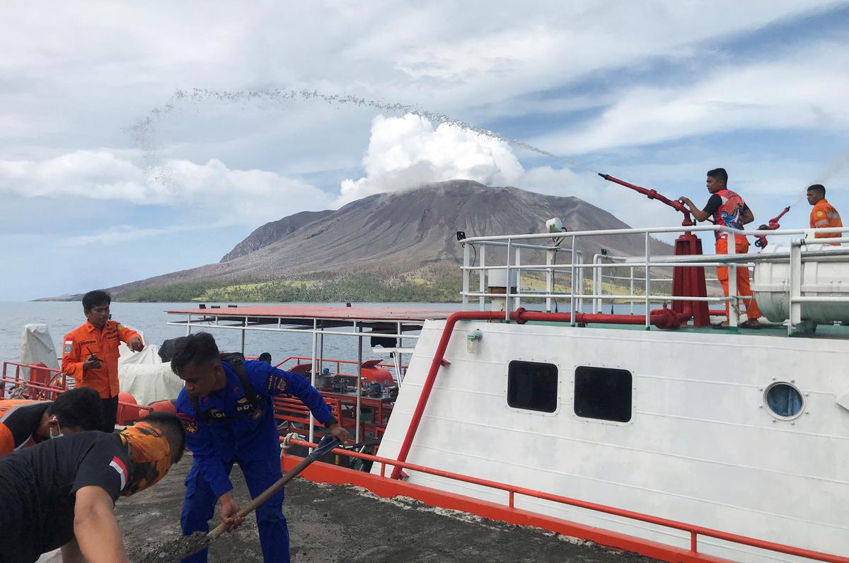 Rescuers spray water while cleaning the volcanic ash following the Mount Ruang volcano eruption in Indonesia’s North Sulawesi province on April 19, 2024.