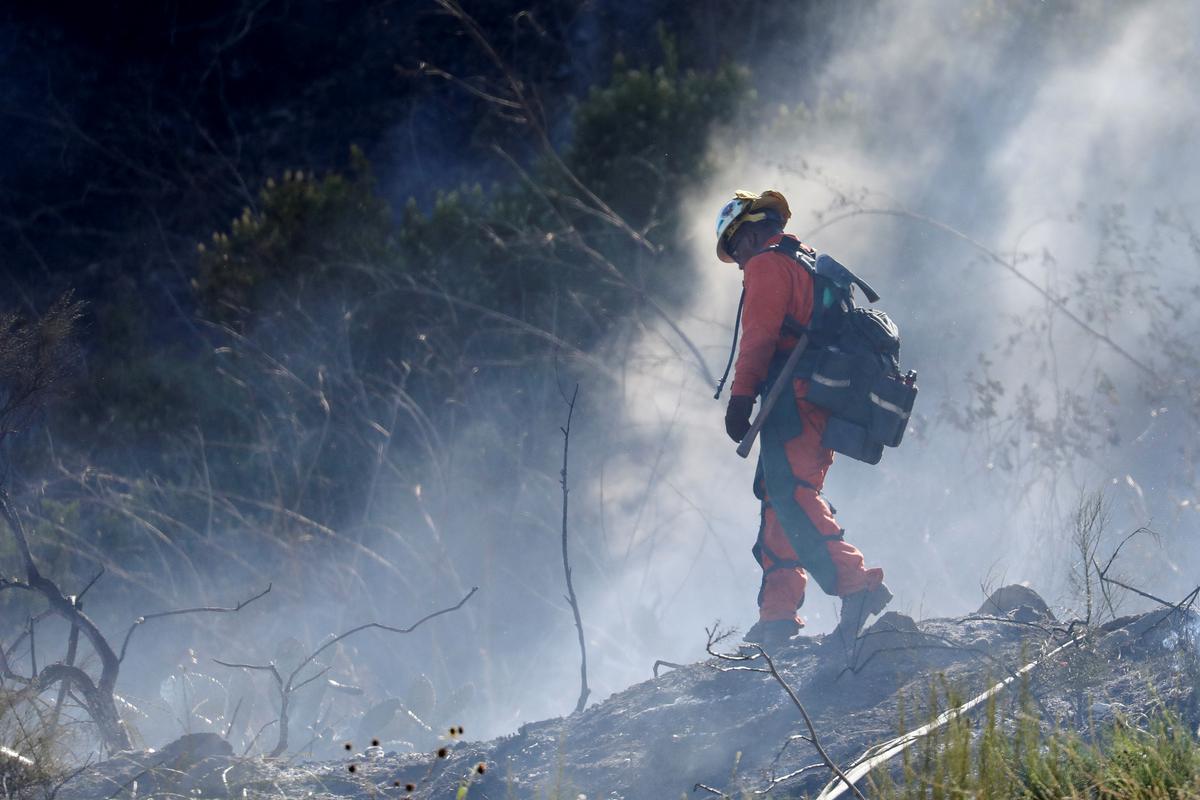 A firefighter aims to control a new wildfire in Duarte, California, June 12, 2022.