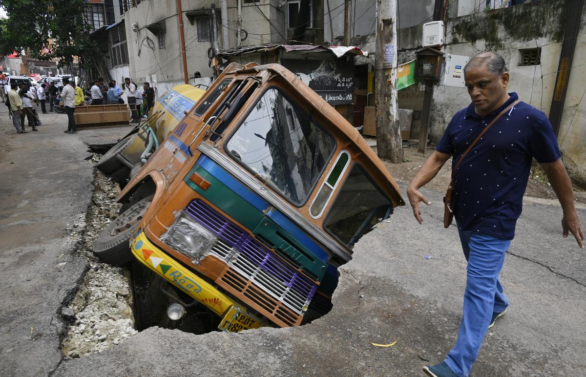 A water tanker plunges after a section of the concrete cover over a drainage channel gave way at Banjara Hills, Hyderabad, on Tuesday, following heavy rain. A water tanker plunges after a section of the concrete cover over a drainage channel gave way at Banjara Hills, Hyderabad, on Tuesday, following heavy rain.