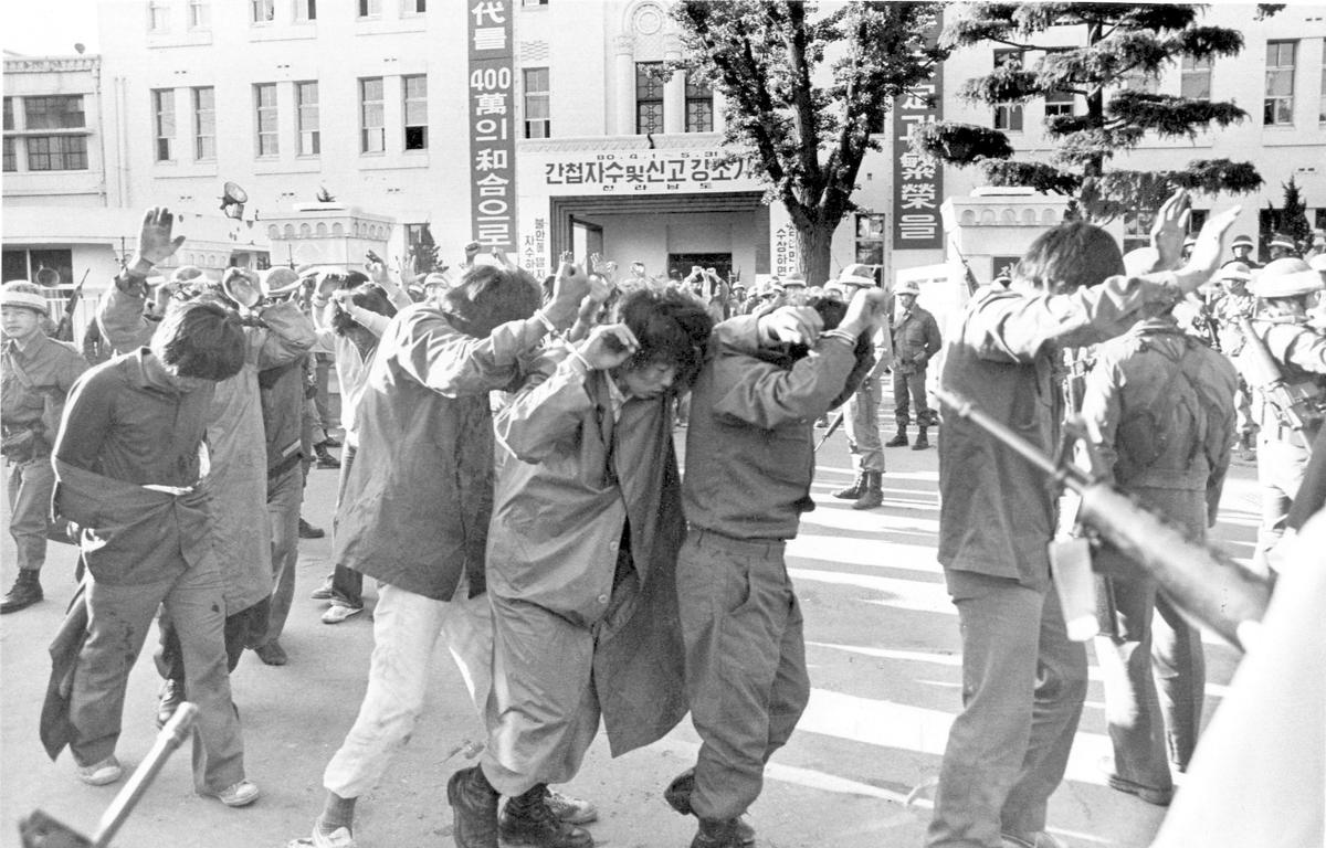 Scores of captured rebels with hands up are being led away on May 27, 1980, by armed soldiers from the provincial government HQ in this city of Gwangju (Kwangju), which South Korean troops recaptured in a firefight earlier in the day.