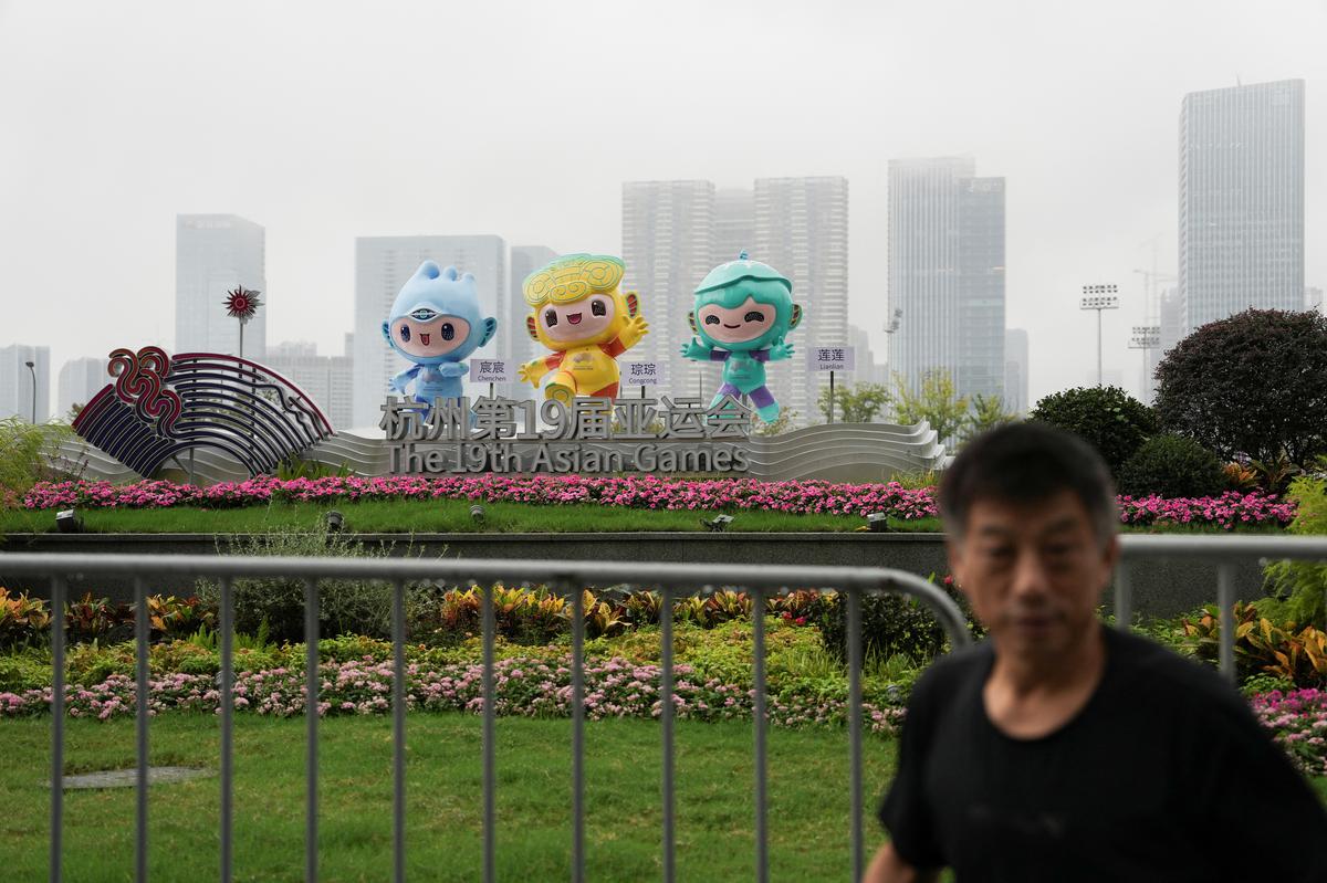 A man stands in front of statues of the three mascots of the 19th Asian Games Hangzhou 2022, near Hangzhou Olympic Sports Centre Stadium, the opening ceremony venue for the Game, in Zhejiang province, China.