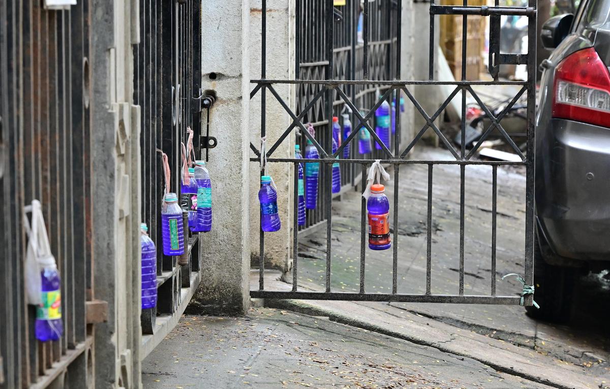 Bottles filled with blue-tinted water outside homes in Saligramam. 