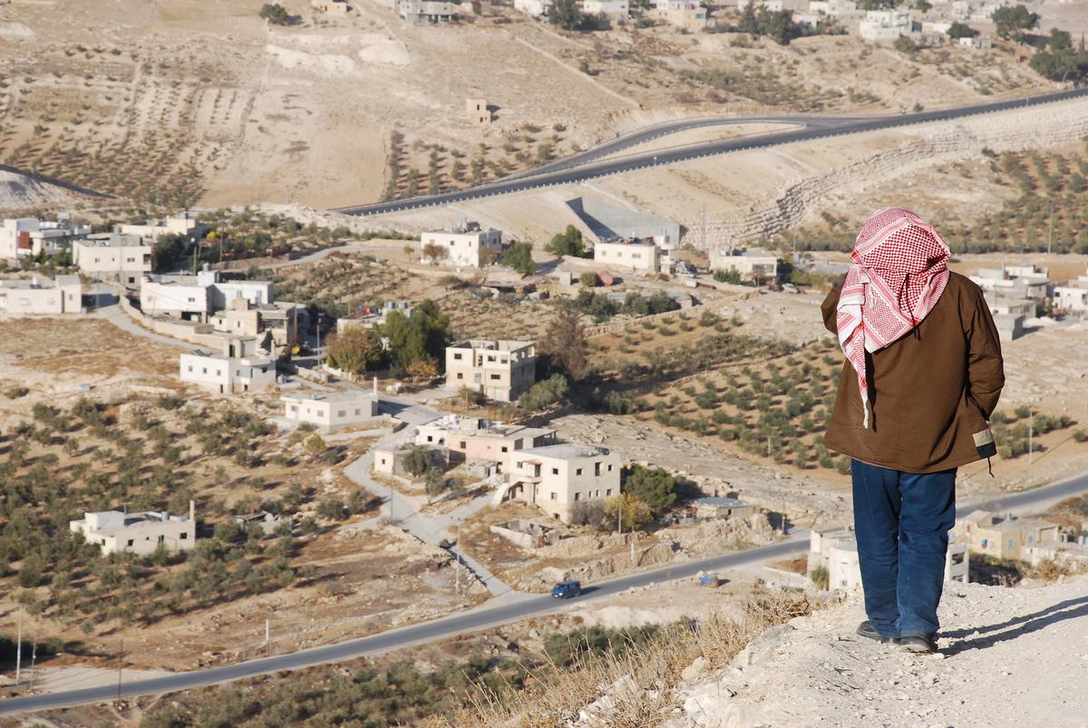 A lone man looking at a village below on the outskirts of the West Bank town of Bethlehem.