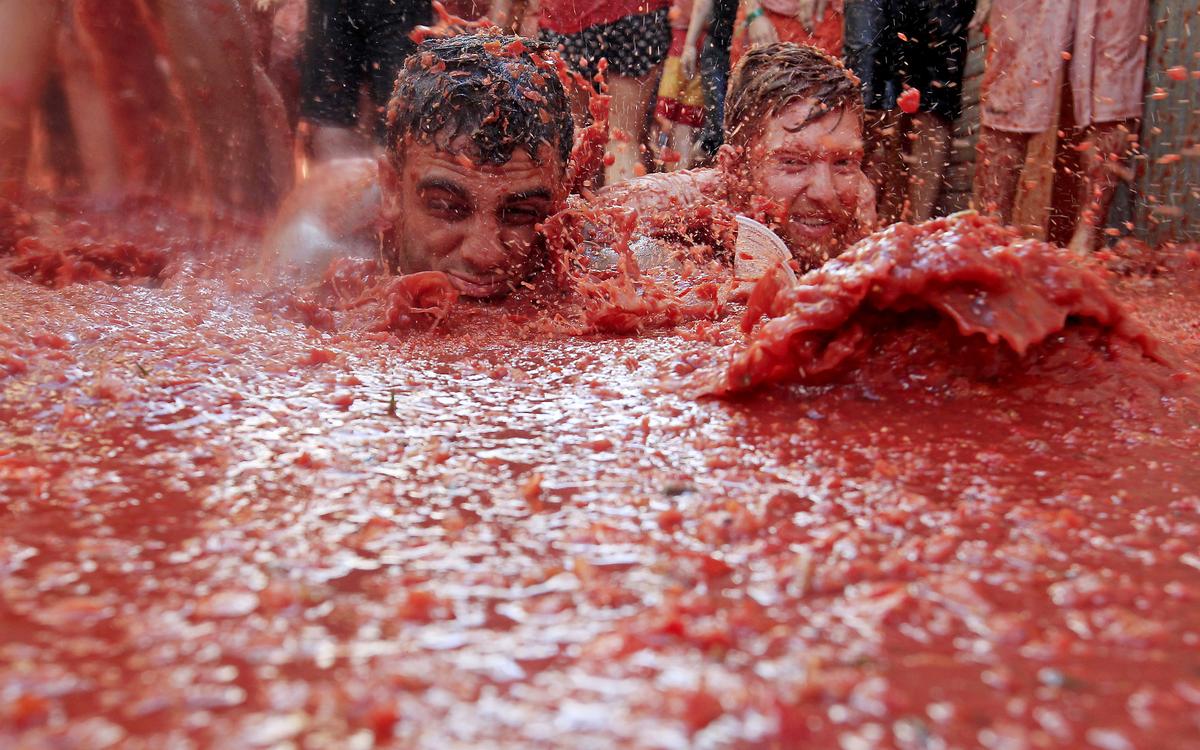 Dwóch mężczyzn leży w kałużu zgrabnych pomidorów podczas corocznej fiesta pomidora „Tomatina” w wiosce Bunol. Dwóch mężczyzn leży w kałużu zgrabnych pomidorów podczas corocznej fiesta pomidora „Tomatina” w wiosce Bunol.