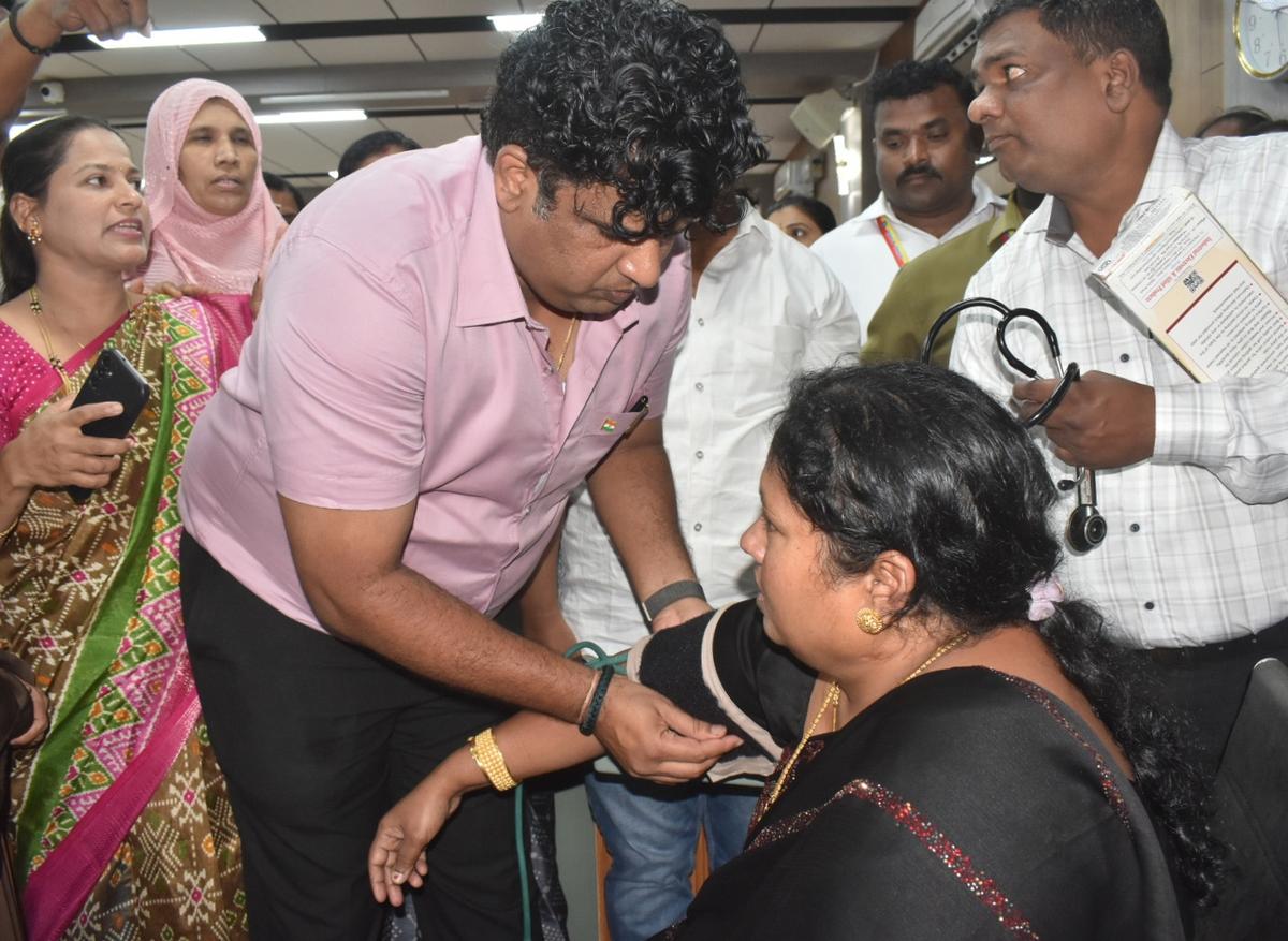 Health Officer Sridhar Dandappanavar checking Congress councillor Suvarna Kallakuntla after she fell down while being carried out by marshals during the monthly council meeting in Hubballi on Wednesday.
