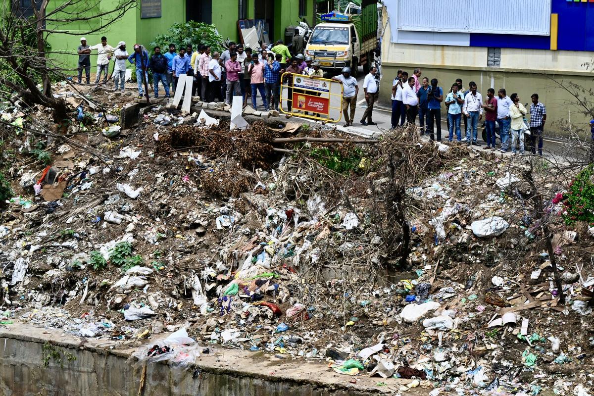 People gather near the storm water where Renukaswamya’s body was found, as police conduct a spot mahajar along with the accused in Bengaluru on June 12, 2024.