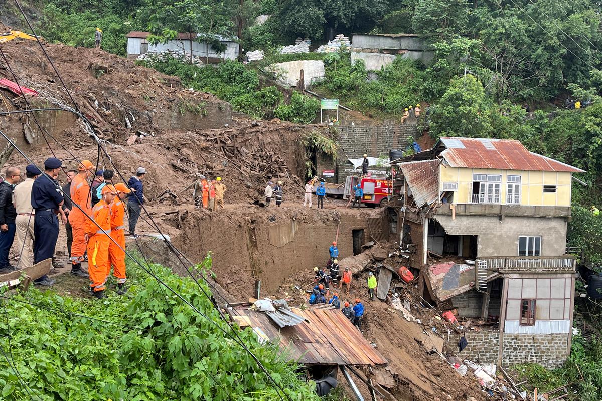 Members of rescue teams look for survivors amidst the debris next to a stone quarry that collapsed following torrential rains brought by Cyclone Remal on the outskirts of Aizawl, Mizoram on May 28, 2024. 