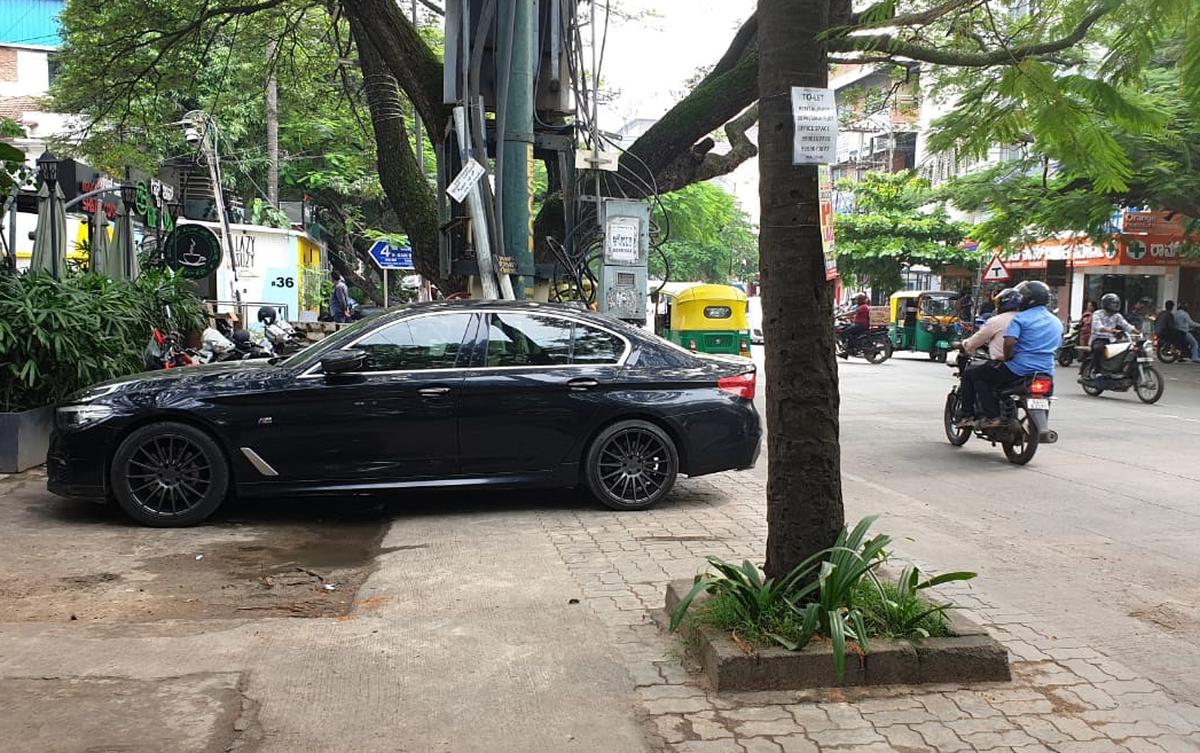 Cars parked across the footpath of 80ft Road developed under the Smart City project.