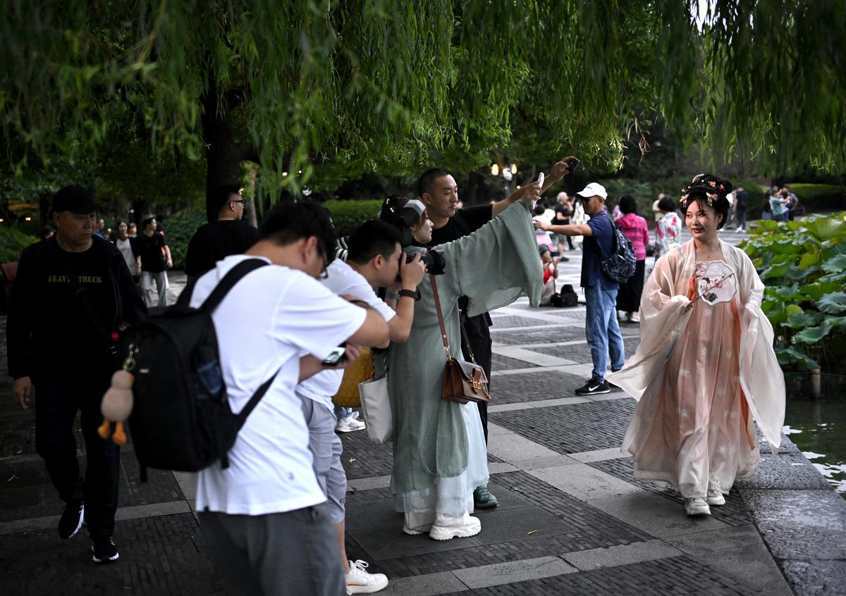 A woman wearing traditional Chinese dress poses for a photography group by West Lake in Hangzhou, ahead of the Asian Games 