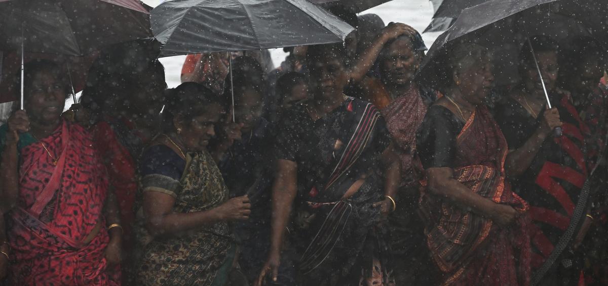 Women react to heavy rain as they attend a protest demanding a comprehensive package for coastal protection amid rising sea levels and flooding threats in the rainy season at Kannamaly in West Kochi on Saturday, May 24, 2025