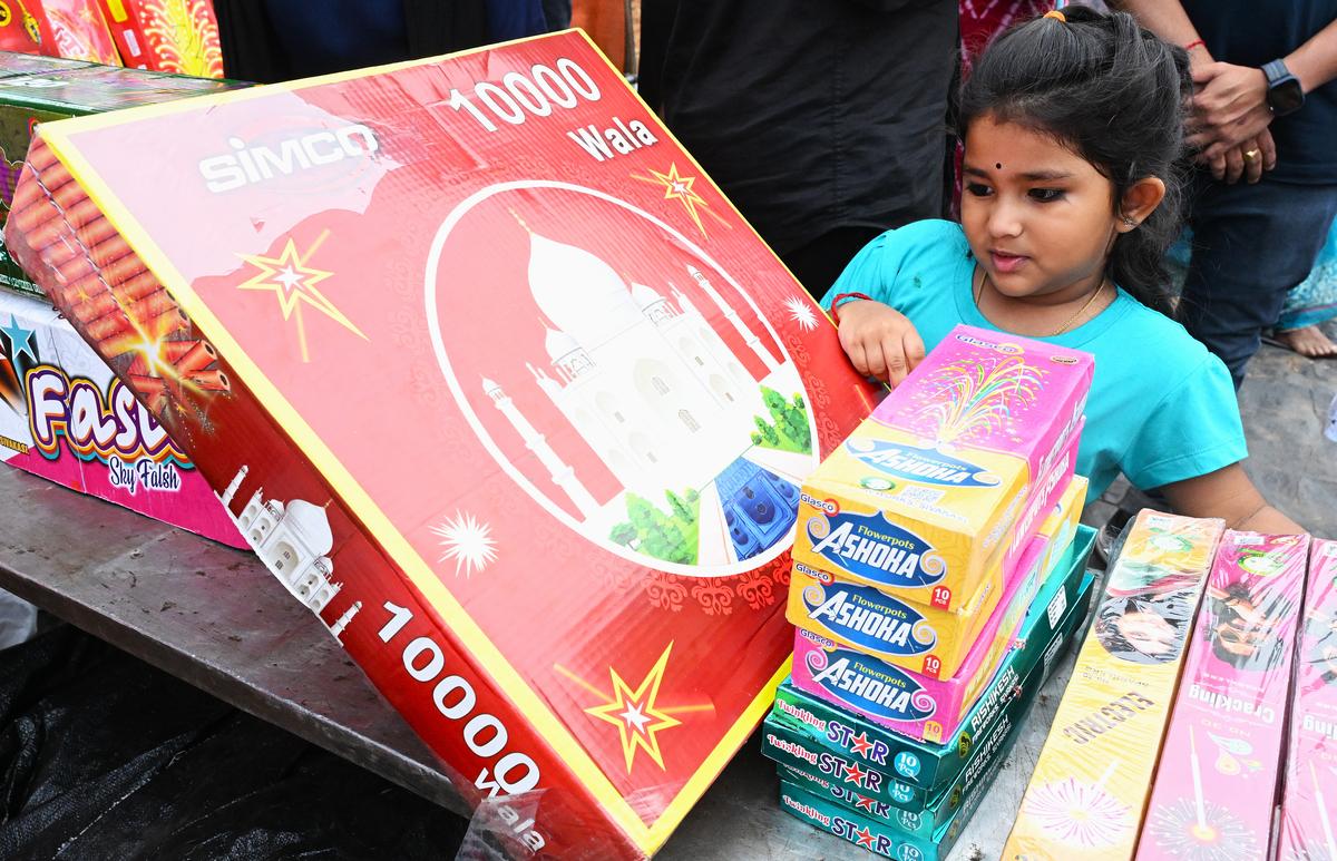Uma menina seleciona fogos de artifício em uma barraca no terreno da Engenharia da UA em Visakhapatnam no domingo. 