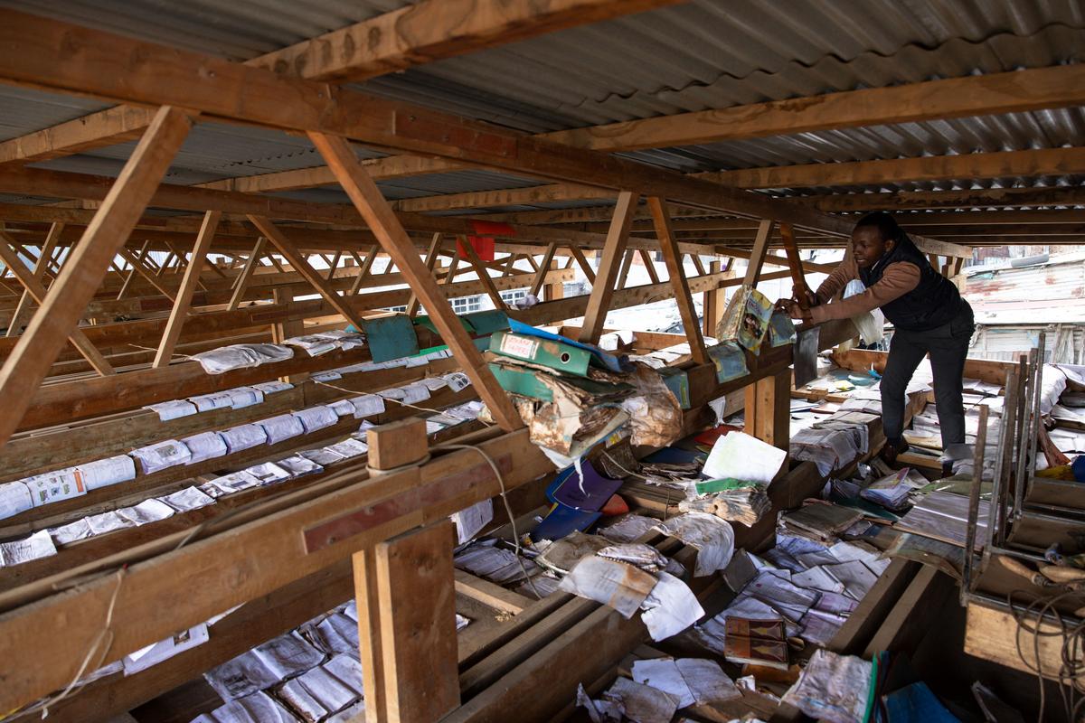 A teacher dries damp books inside the ceiling of a classroom that was previously affected by floods in Mathare slum of Nairobi, Kenya on May 13, 2024