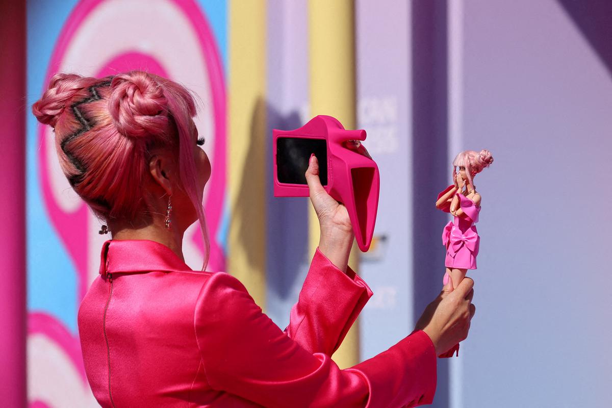 A fan takes a photo of a Barbie doll at the world premiere of the film ‘Barbie’ in Los Angeles, California