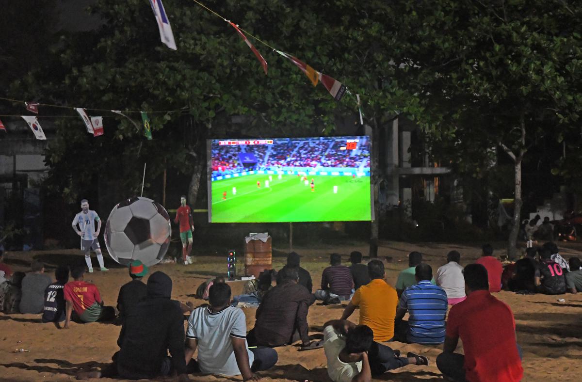 Football fans watch on the screen installed in a field during the Qatar 2022 World Cup quarter-final football match at Thoothoor village in Kanyakumari district on December 10, 2022.