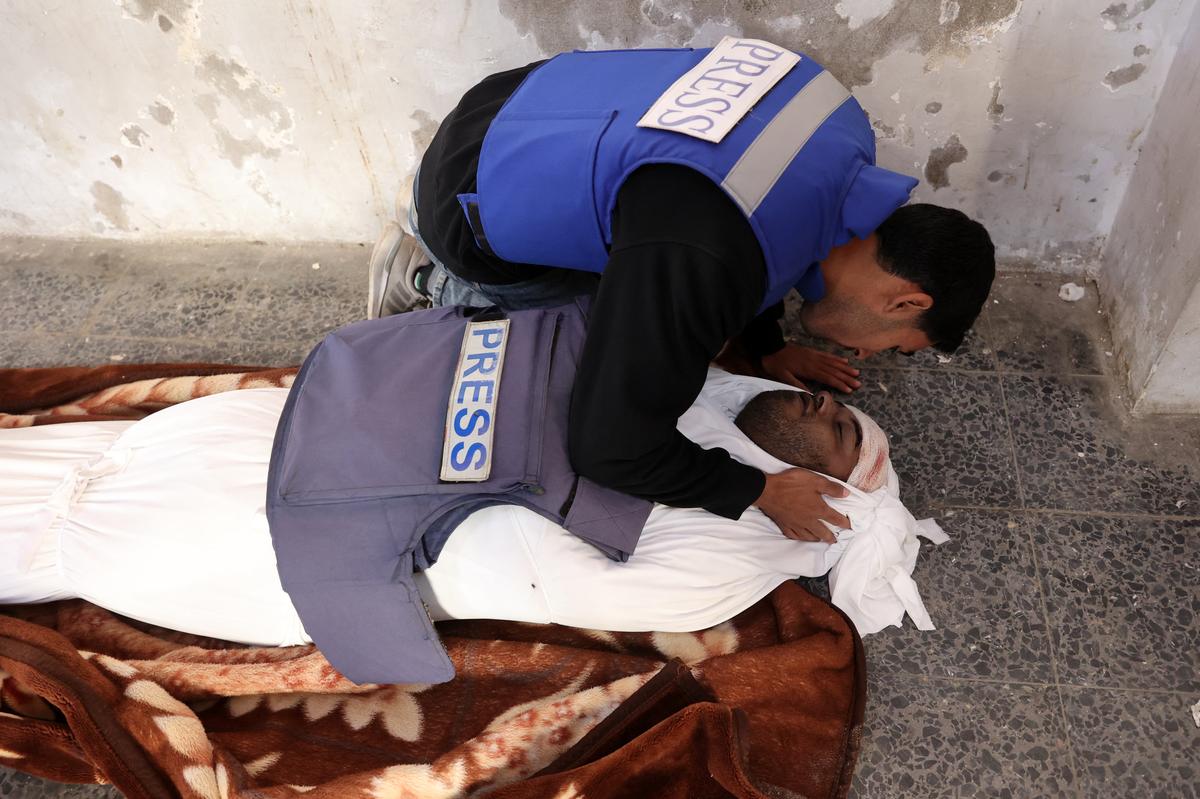  A colleague kneels in front of the body of local Palestinian journalist Mamduh Qantiya who was killed in an Israeli strike, ahead of his funeral at the al-Maamadani hospital in Gaza city in the northern Gaza Strip on December 1, 2024, amid the ongoing war between Israel and the Hamas militant group. 