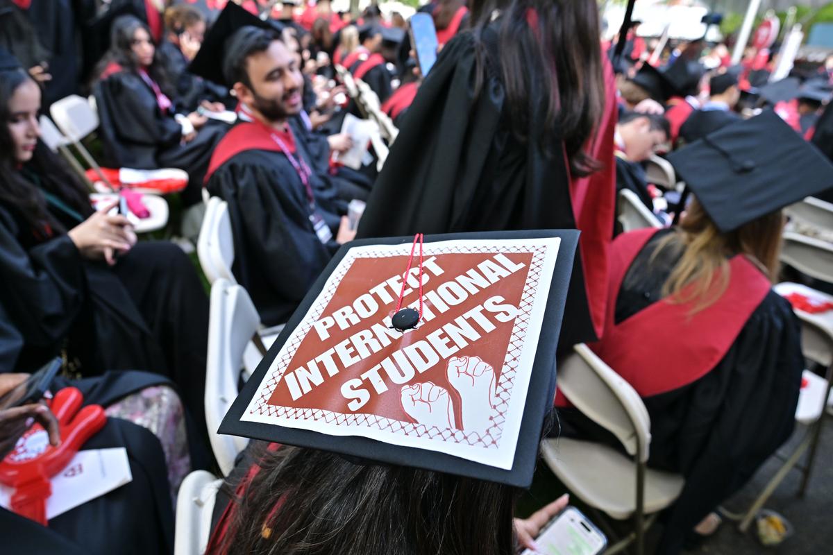 CAMBRIDGE, MA - MAY 29:  A Harvard University graduate with a message in support of international students on her mortarboard sits with fellow students at the start of commencement exercises at Harvard University in Harvard Yard May 29, 2025, in Cambridge, MA. (Photo by Josh Reynolds/For The Washington Post via 