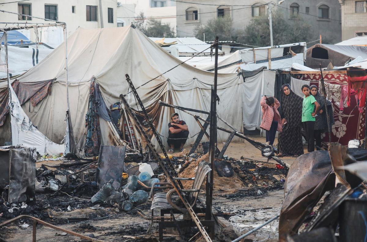 Palestinians survey damage at the site of an Israeli attack on tents sheltering displaced people, amid the Israel-Hamas conflict, at the Al-Aqsa Martyrs Hospital in Deir al-Balah, central Gaza Strip, October 14, 2024.