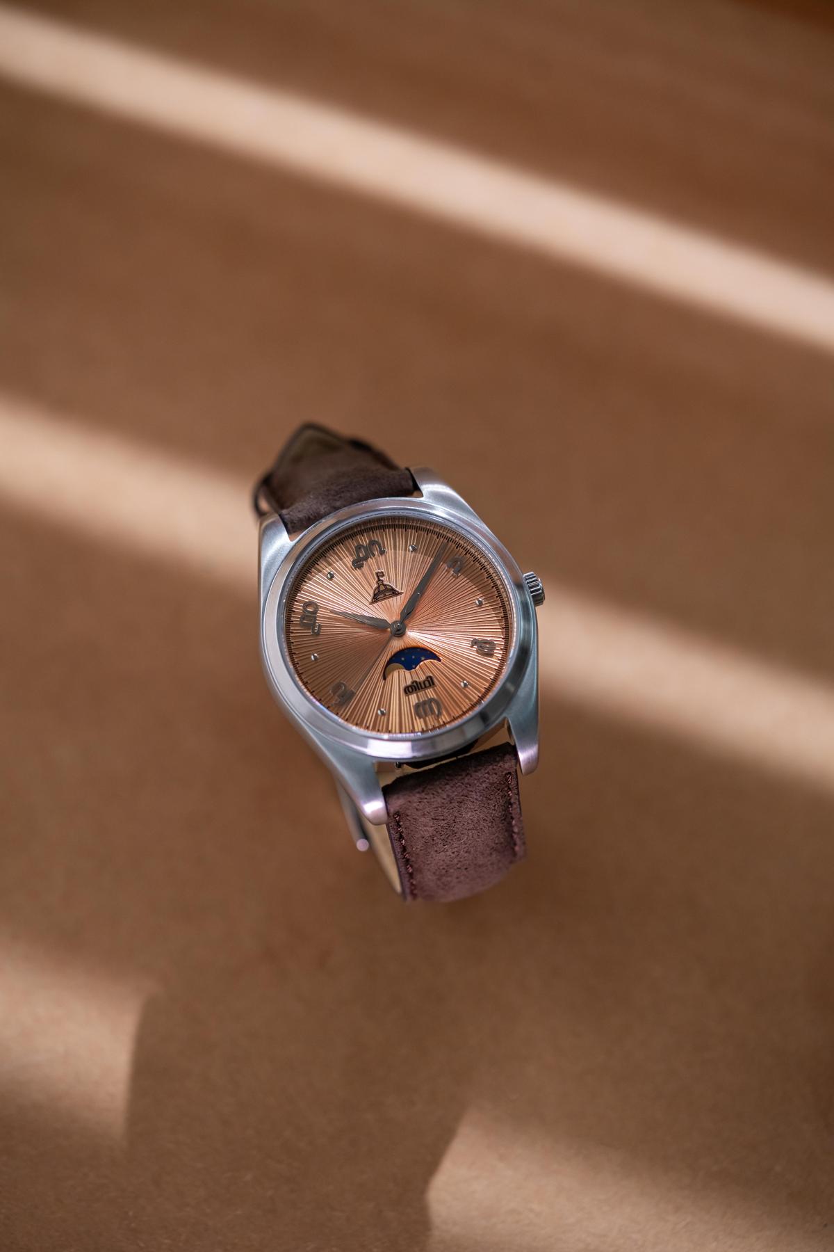 मलयालम डायल वाली सैल्मन रंग की घड़ी 