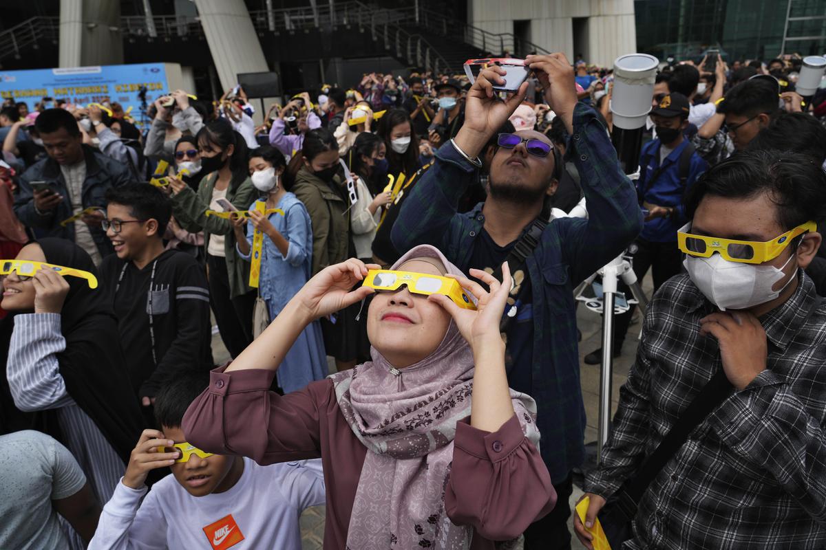 People use protective glasses to watch a solar eclipse on April 20, 2023 in Jakarta, Indonesia.  A rare solar eclipse will pass through remote parts of Australia, Indonesia and East Timor on Thursday. 