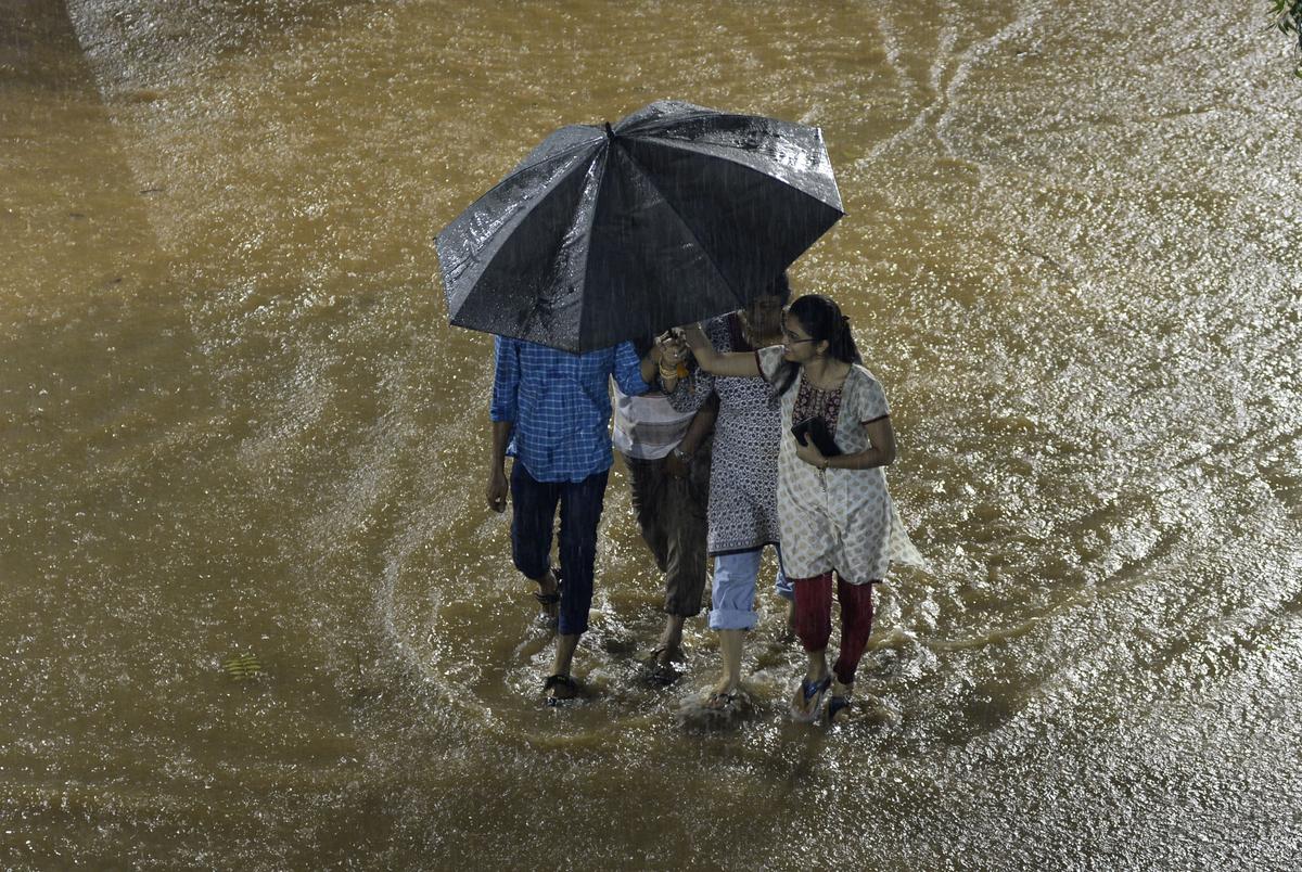 Youngsters share an umbrella in the heavy rain.