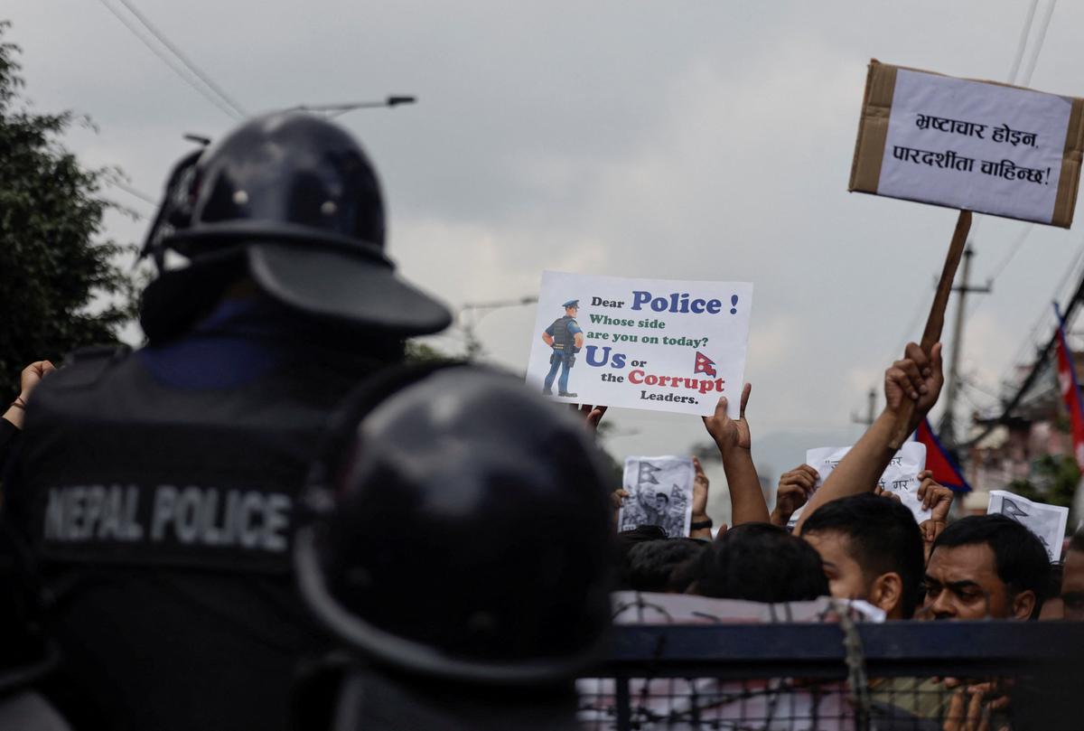 Demonstranti, kas tur plāksnītes, atrodas aiz barikādes protesta laikā Katmandu, Nepālā, 2025. gada 8. septembrī.