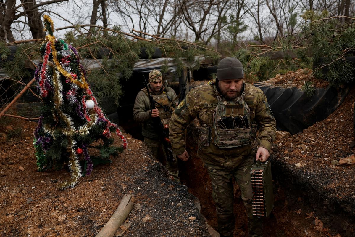 Ukrainian servicemen with the Dnipro-1 Special Tasks Patrol Police regiment Raphael Karapitian 45 and Roman Kapinus 39, walks with with weapons beside a decorated Christmas tree in the trenches on the front line, as Russia’s attack on Ukraine continues, on Christmas Eve in Bakhmut, Ukraine on December 24, 2022.