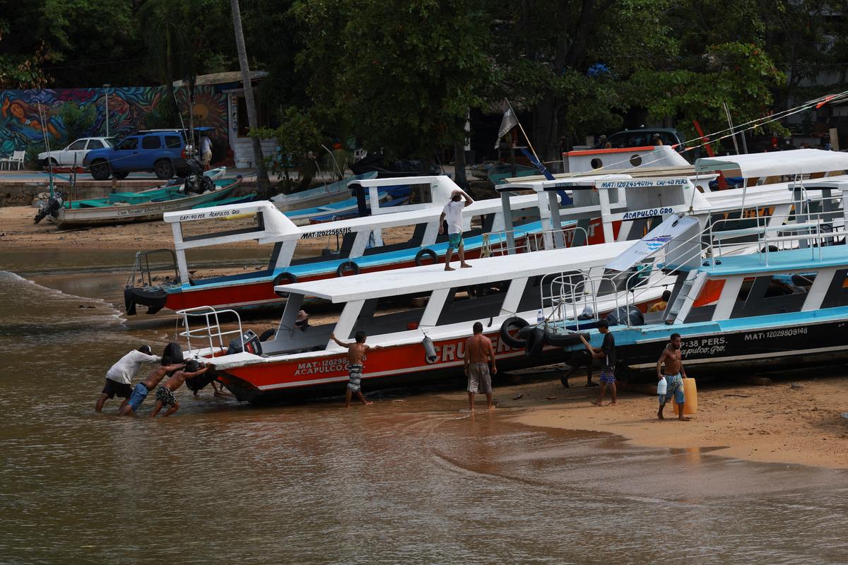 People move a boat to safety as Hurricane Erick strengthens off Mexico’s Pacific Coast, in Acapulco, Guerrero state, on June 18, 2025.