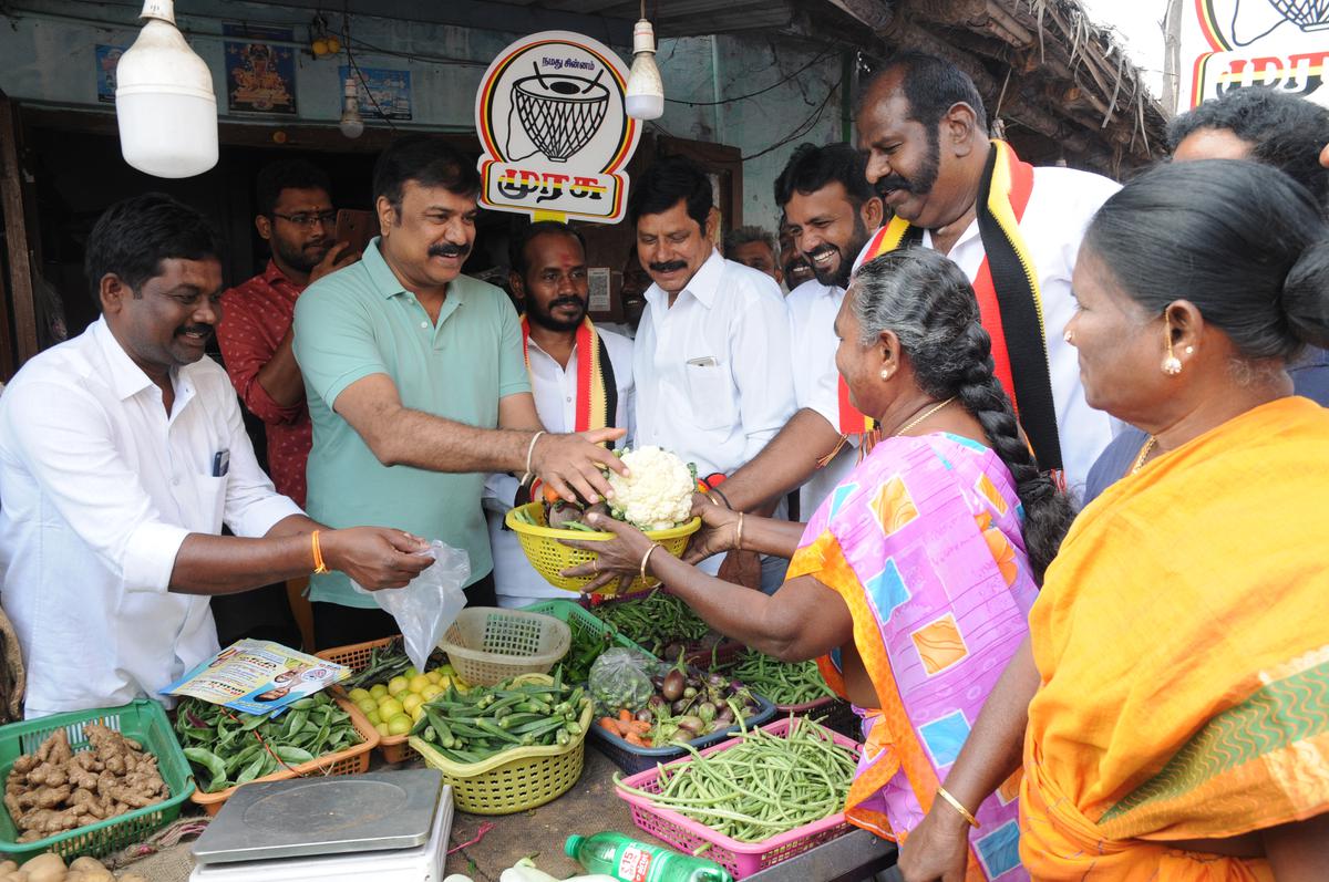 DMDK Deputy General Secretary LK Sudhish selling vegetables at a shop in Erode on February 14, 2023, party candidate S.  Seeking votes for Anand.