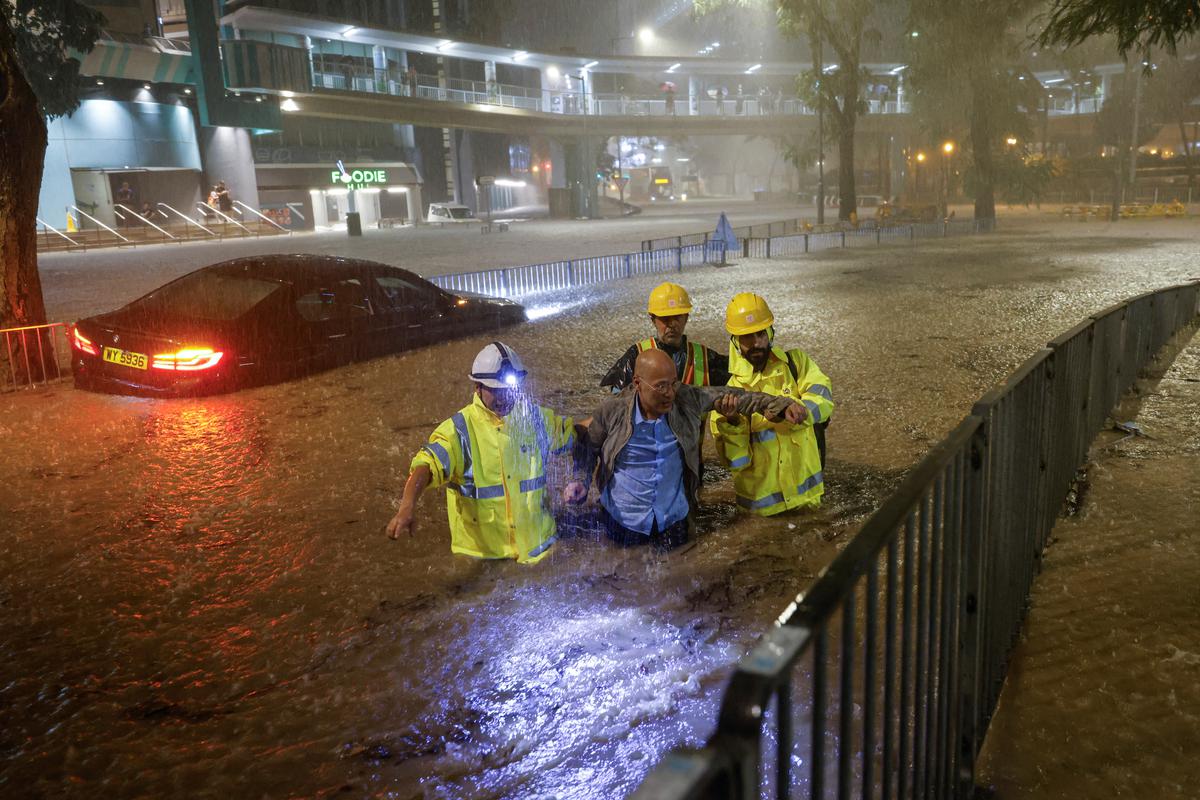 Drainage workers assist a driver stranded due to flooding to a safe place, during heavy rain in Hong Kong, on September 8, 2023