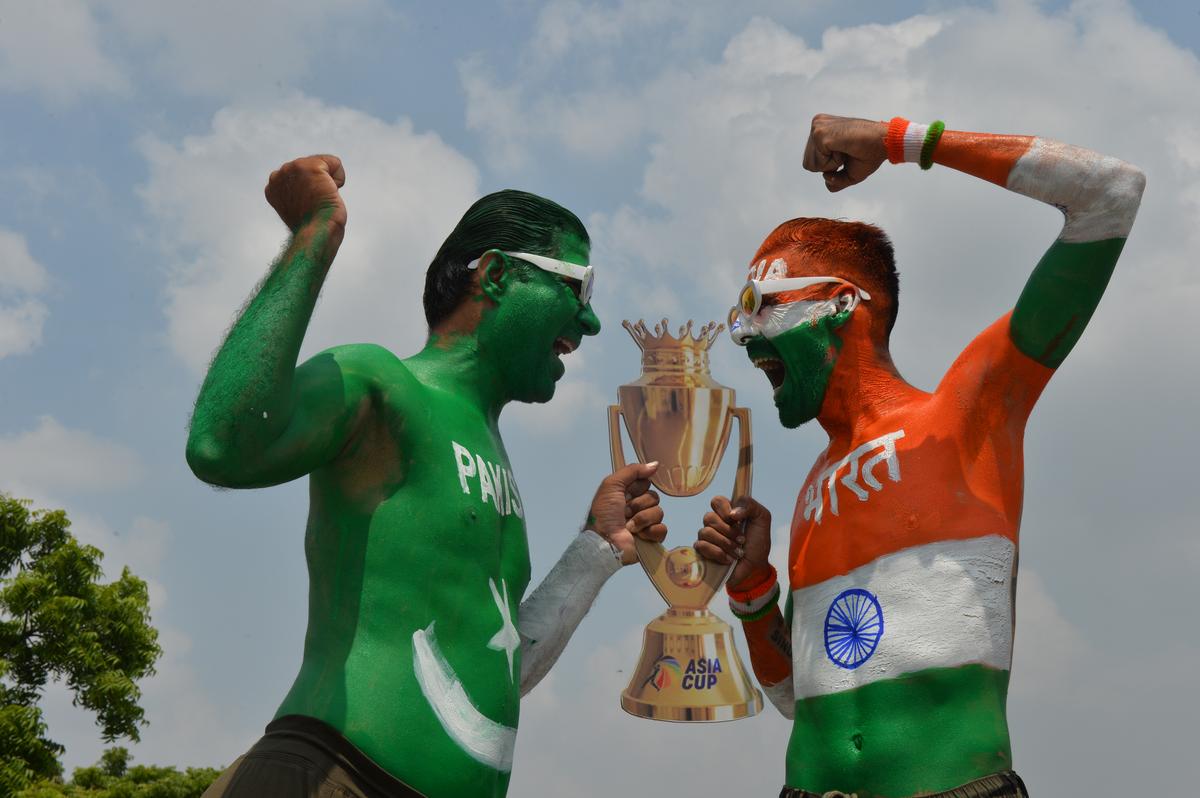 Indian fan Arun Haryani (Indian Tricolour) and Jagdish Purswani (Pakistani Colour) strike a pose with Asia Cup Trophy and Brahmos Missiles ahead of the Asia Cup Cricket match between India and Pakistan in Dubai, in Ahmedabad on Saturday, September 13, 2025. 