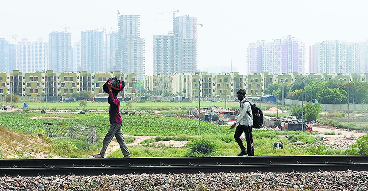 Migrant workers carrying their belongings and with their faces covered walk along a railway track to return to their home state of eastern Bihar, during an extended nationwide lockdown to slow the spread of the coronavirus disease (COVID-19), in Ghaziabad. File