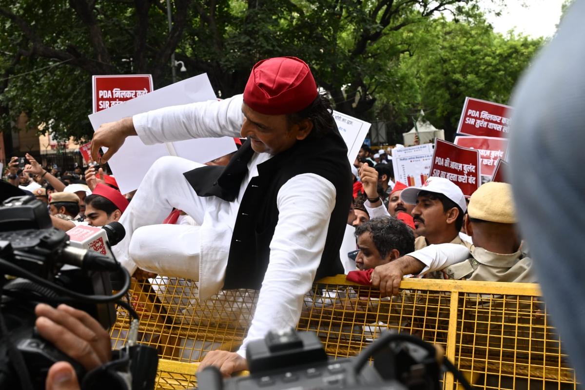 Samajwadi Party Supremo Akhilesh Yadav climbing over a barricade during the march to the ECI office on August 11, 2025.