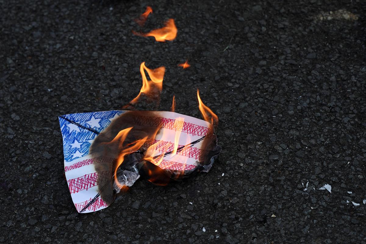 A poster depicting U.S. flag burns on the ground during an anti-U.S. protest, following its attack on Venezuela, and the capture of President Nicolas Maduro and his wife Cilia Flores, outside the U.S. Embassy in Jakarta, Indonesia, January 5, 2026. 