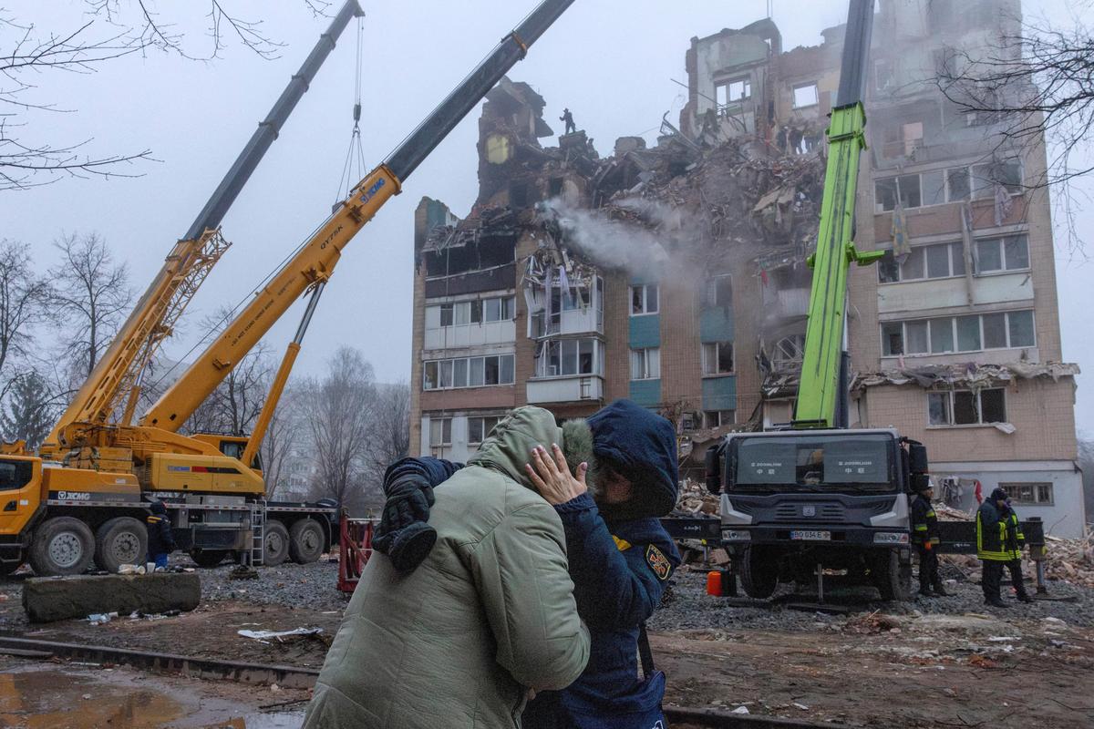 A psychologist comforts a resident on November 20, 2025 in front of an apartment building that was hit by a Russian missile the previous day, amid Russia's attack on Ukraine, in Ternopil. 