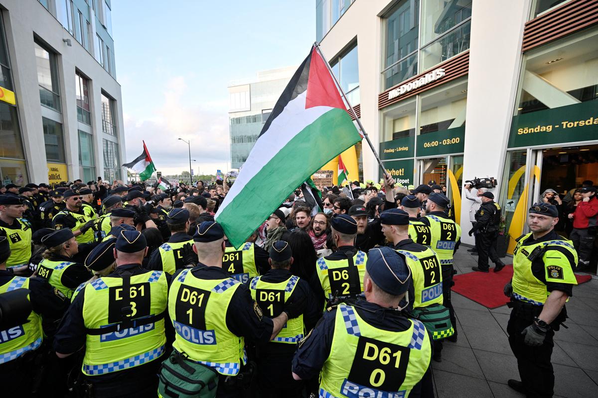 A protester holds a Palestinian flag as police officers stand guard on the day of the “Stop Israel” demonstration, against Israel’s participation in the Eurovision Song Contest due to its ongoing offensive in Gaza