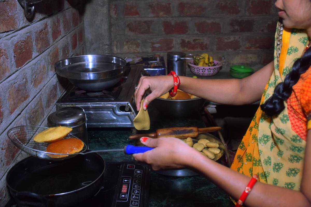 modern black induction stove, Woman standing in kitchen cooking food with spoon, fried chapati(puri) Inducation