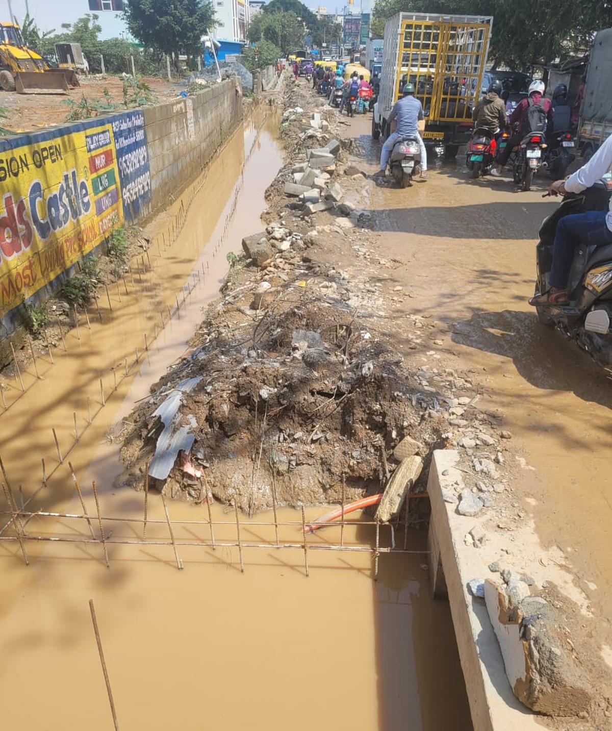 Drain work has been left incomplete for several months, resulting in open trenches, severe road damage, and daily suffering for thousands of residents and commuters. 