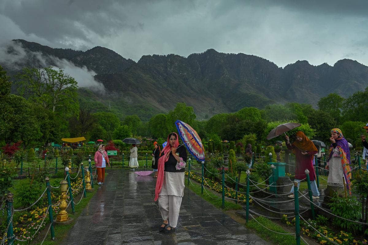 Visitors enjoy it in the Mughal garden during the rainfall in Srinagar. 